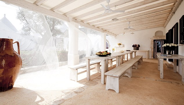 Light and breezy outdoor dining area with long table and pews